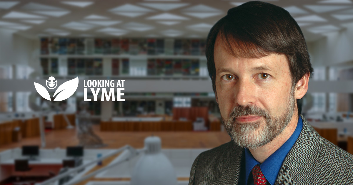 Dr Brian Fallon, M.D., avec le logo Looking at Lyme, devant une bibliothèque.