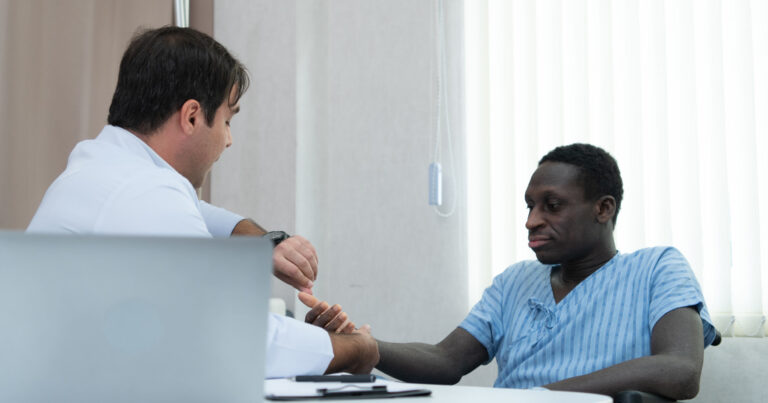 Un médecin blanc vérifie le pouls d’un patient noir.
