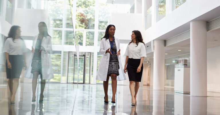 Two women walk down the hall in a large research facility.